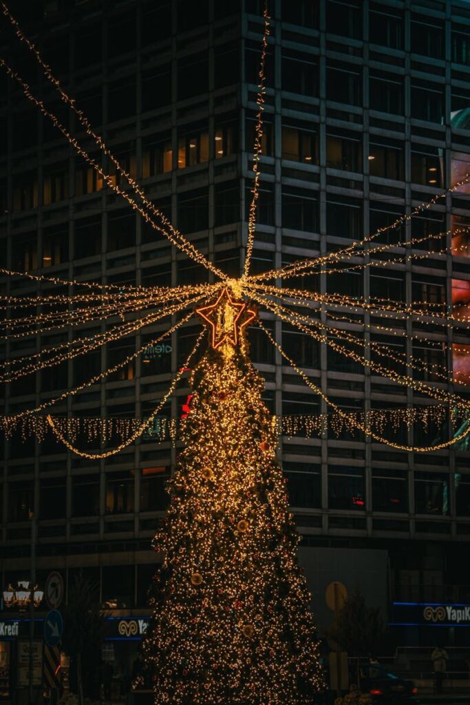 A beautifully decorated Christmas tree with star topper in a bustling urban setting.